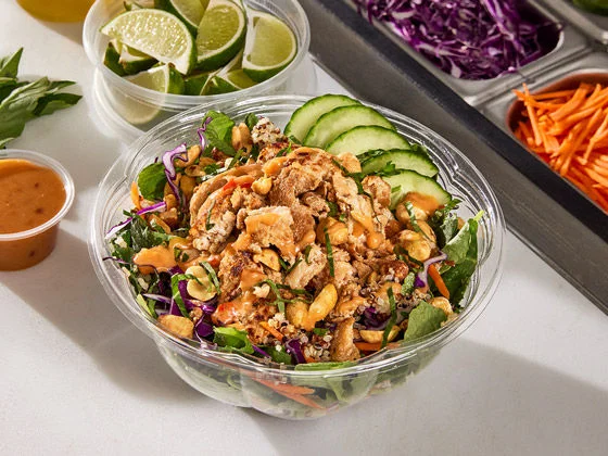 Chicken quinoa bowl with veggetables, cucumbers, limes and sauce on the side