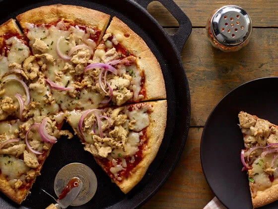 BBQ chicken pizza on balck board and a slice of pizza on a black plate