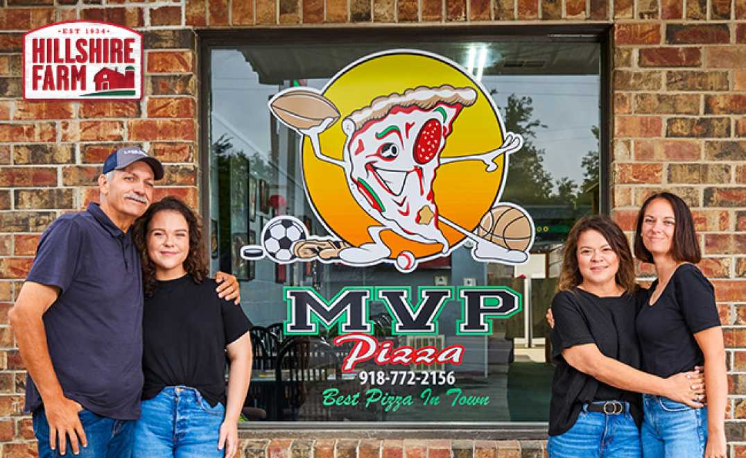 MVP Pizza window logo with the owners and employees taking a picture in front of it