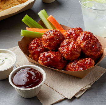 Boneless spicy chicken wings with a side of veggies and sauces